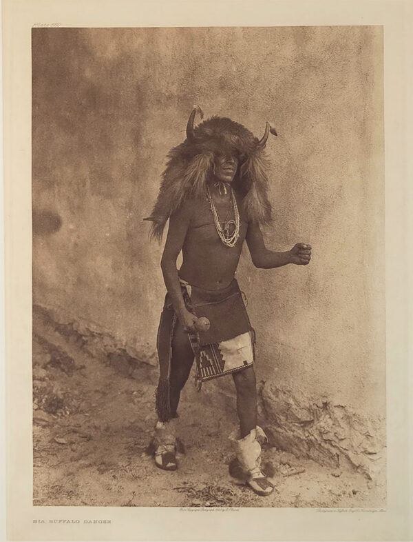 A man in native dress standing on the ground.