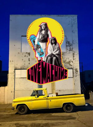A yellow truck parked in front of a mural.