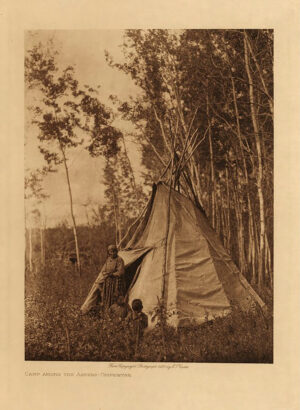 A man sitting in front of a tent on the grass.