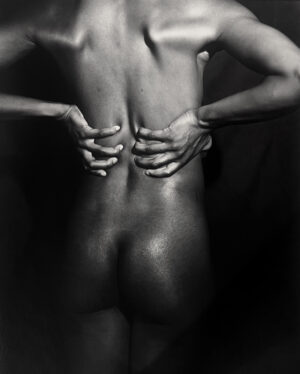 A woman with her hands on the back of her body.