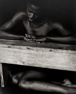 A black and white photo of two people sitting on top of a wooden box.