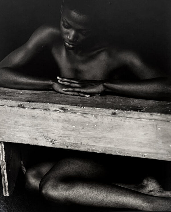 A black and white photo of two people sitting on top of a wooden box.