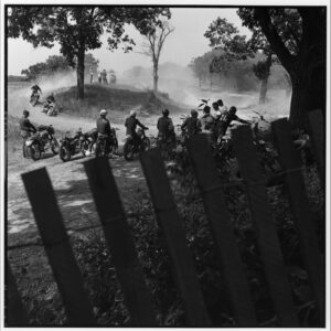 A group of people riding motorcycles on top of a dirt road.