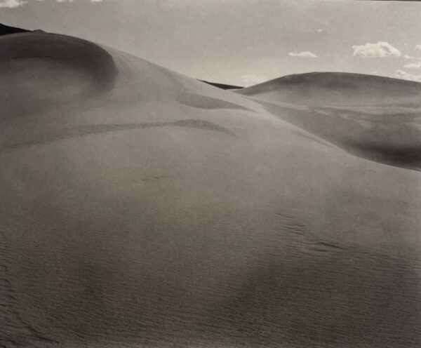 A black and white photo of sand dunes in the desert.