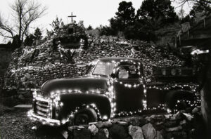 A black and white photo of an old truck with christmas lights.