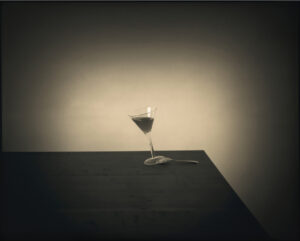 A glass of wine on the table in front of a wall.