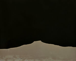 A black and white photo of a mountain with dark sky.