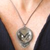 A woman wearing a necklace with an image of a bird in it.