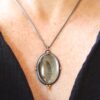 A woman wearing a necklace with a feather on it.