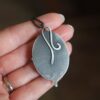 A person holding a leaf shaped metal object.