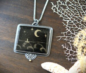 A necklace with a picture of the moon and stars.