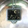 A silver tray with a necklace and a picture of the moon.