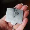 A person holding up a metal object with a wire design.