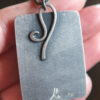 A person holding a metal tag with a wire design on it.