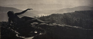 A black and white photo of a person laying on top of a rock.