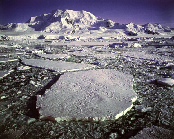A large piece of ice on the ground near some mountains