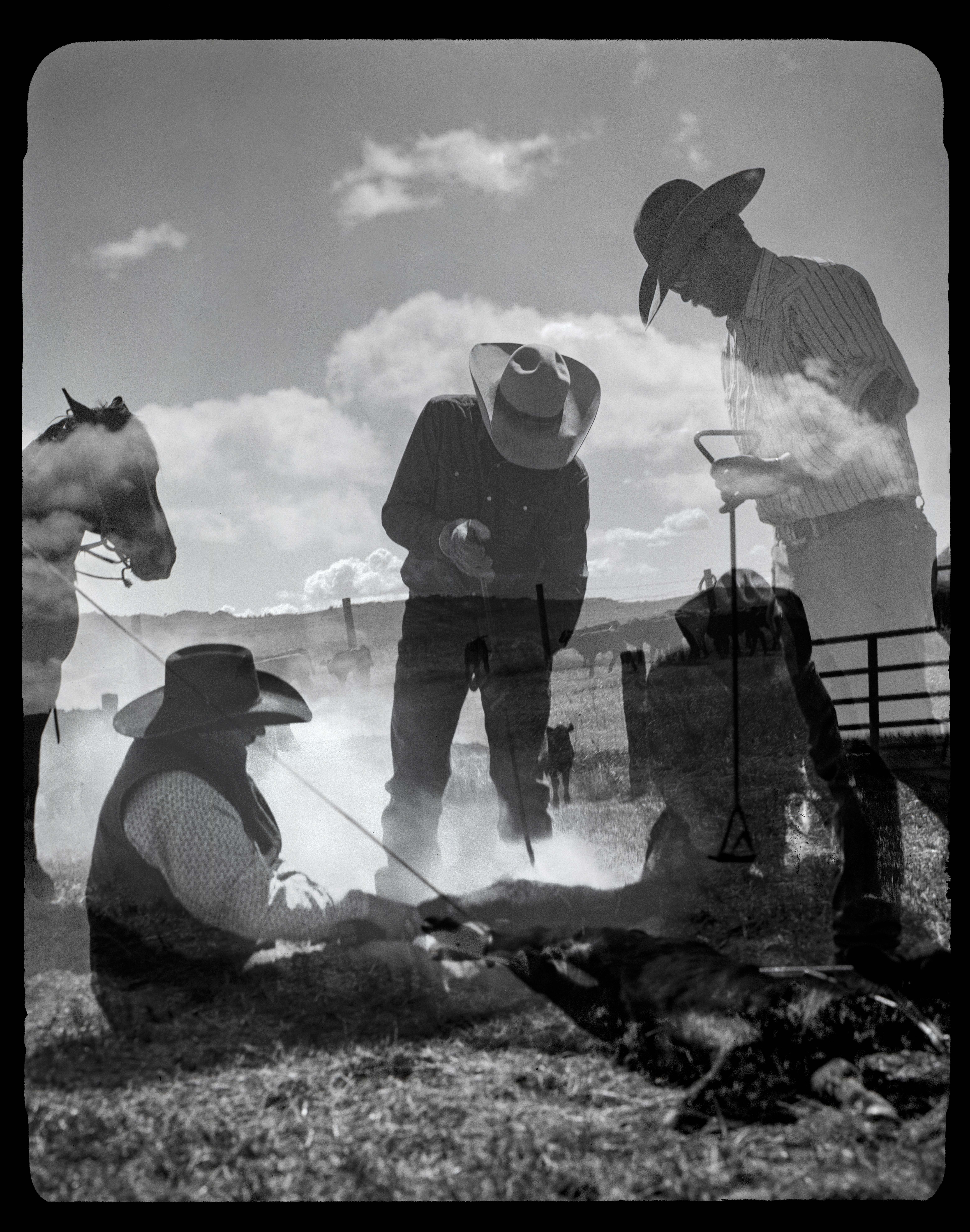 A black and white photo of people with horses.