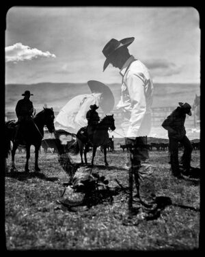 A man in cowboy hat standing next to horses.