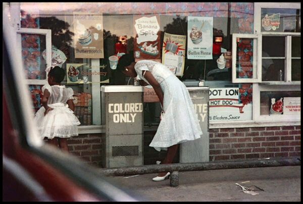 A woman in white dress and heels looking at posters.
